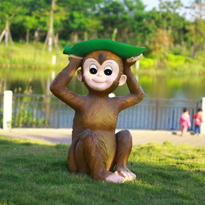 猴子雕塑-公園草地上擺放的頭戴樹(shù)葉的玻璃鋼猴子雕塑高清圖片